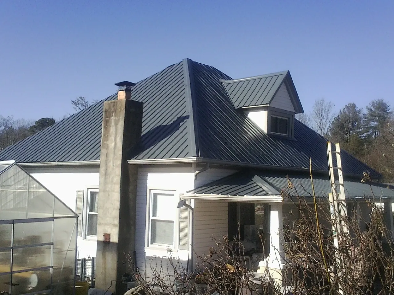 Dark blue standing seam metal roof on a white farmhouse with dormer — Slate & Tile Roof Repair by Roofing Brothers in Napanoch