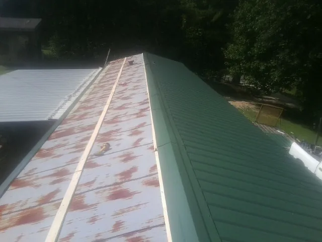 Old rusted panels beside newly installed green metal roofing — Wind Damage Roof Repair by Roofing Brothers in Napanoch