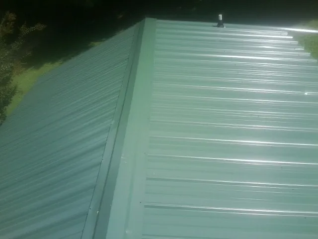 New green metal panels meeting at the ridge of a roof — Flat Roof Repair work by our crew in Napanoch