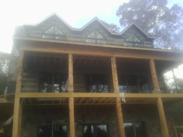 Dormers and porch framing on a large log home under construction — Roof Coating work by our crew in Napanoch