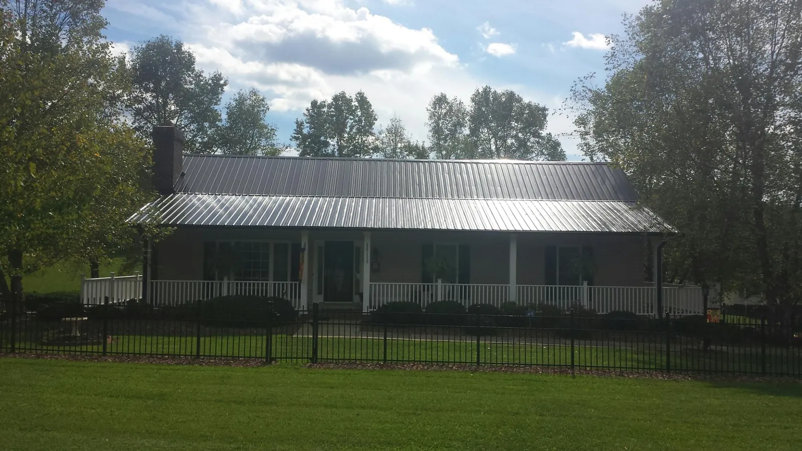 Gray metal roof on a brick ranch with a full width front porch — Gutter Guard Installation work by our crew in Napanoch