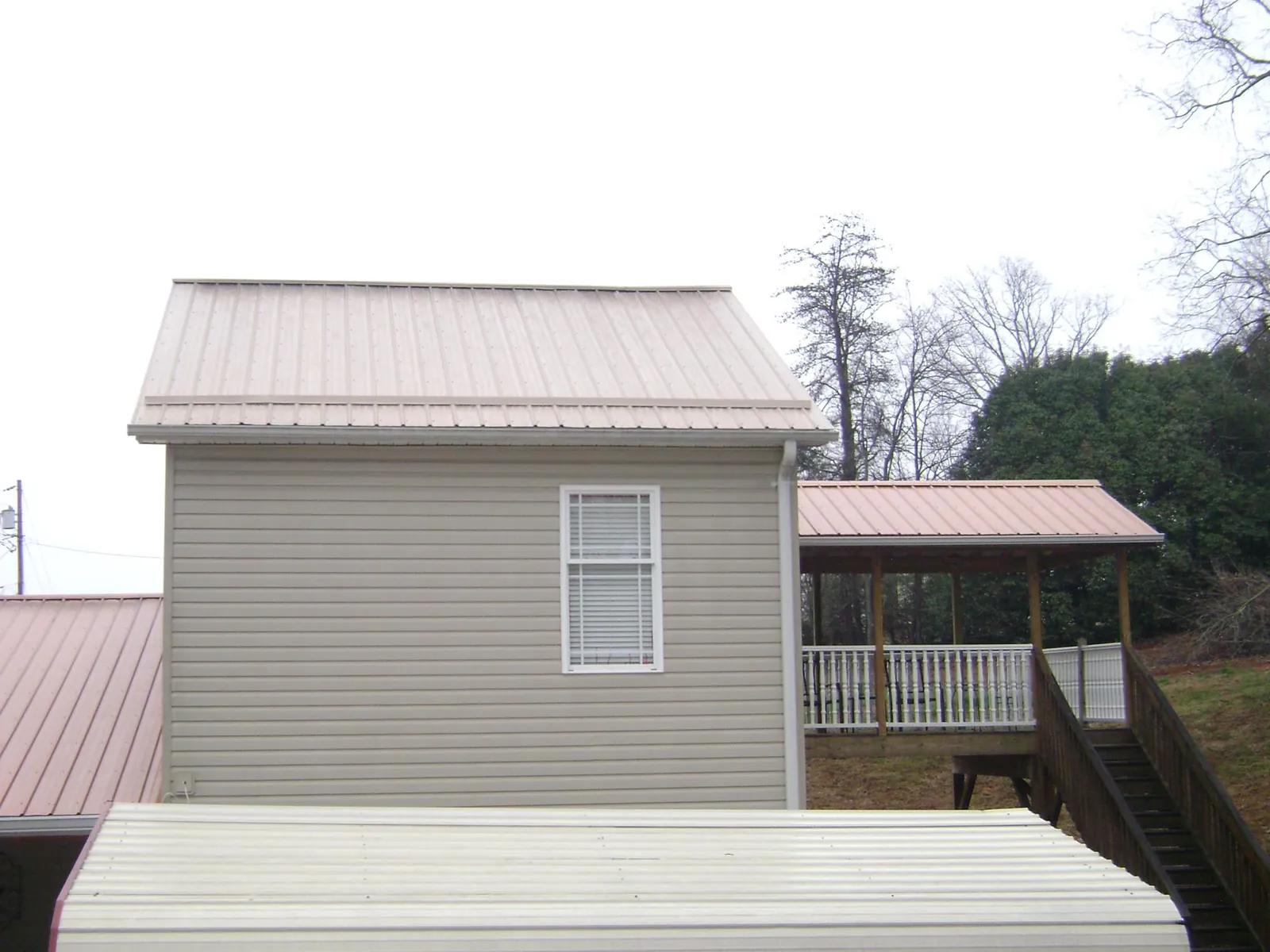 Tan metal roofs on a two story addition and attached porch, from a Roof Replacement job in Napanoch