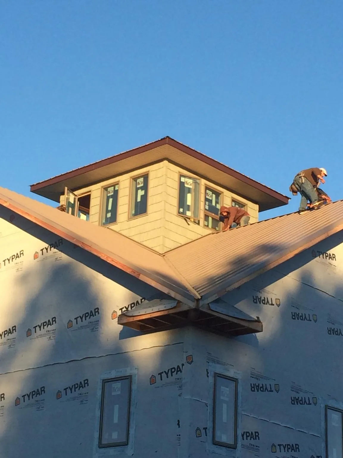 Roofers working around a rooftop cupola on a new metal roof at sunset — Roof Waterproofing in Napanoch by Roofing Brothers